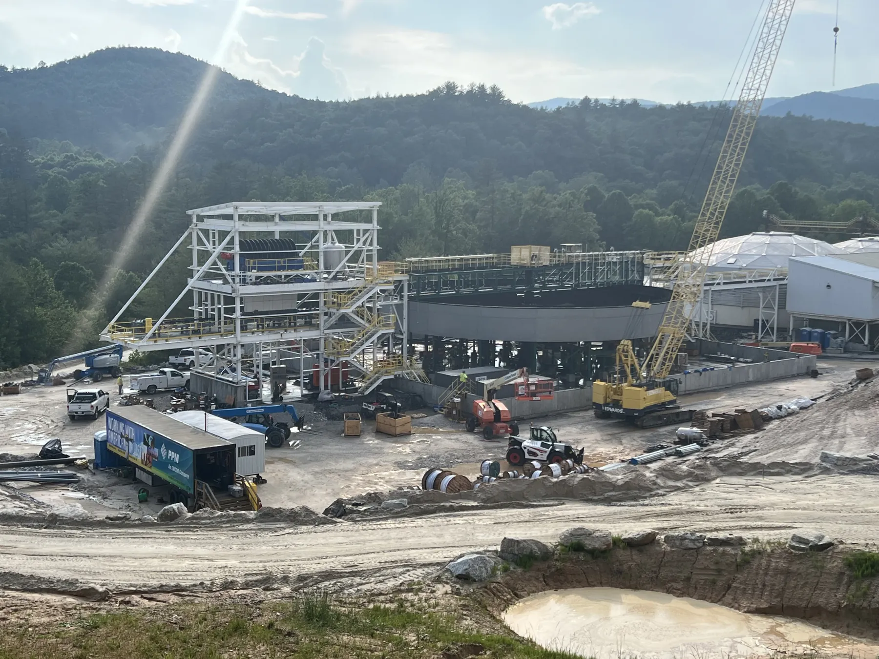 Industrial minerals processing plant under construction, with structural steel, crawler crane and site works in a mountain valley